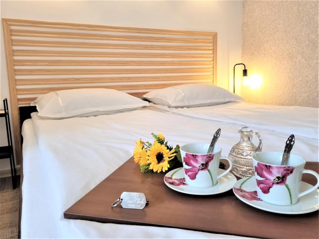 a tray with two cups and flowers on a bed at Casa Eladi in Eforie Sud