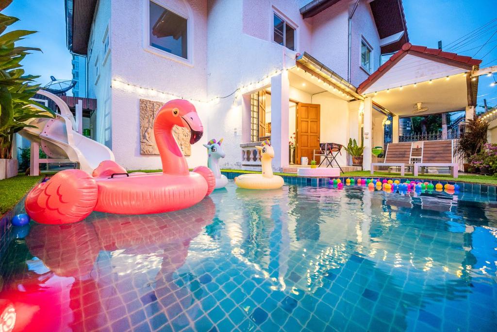 una piscina con 3 flamencos inflables en una casa en Wongamart Pool Villa en Pattaya North