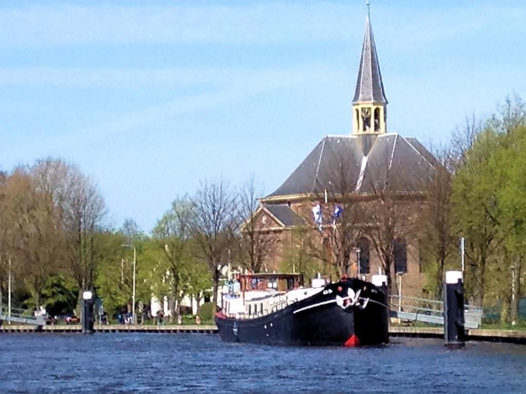 een boot in het water voor een kerk bij Hotelschip 'Ali-B2' in Alphen aan den Rijn