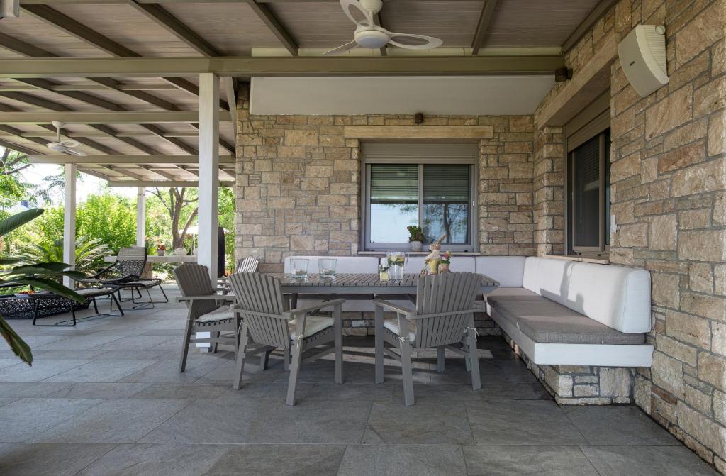 eine Terrasse mit einem Sofa, einem Tisch und Stühlen in der Unterkunft Ammouda Villas in Ormos Panagias
