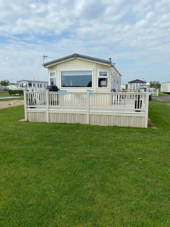 una pequeña casa con una valla blanca en el césped en L&g FAMILY HOLIDAYS MILLFIELDS 6 BERTH FAMILYS ONLY AND THE LEAD PERSON MUST BE OVER 30s, en Ingoldmells