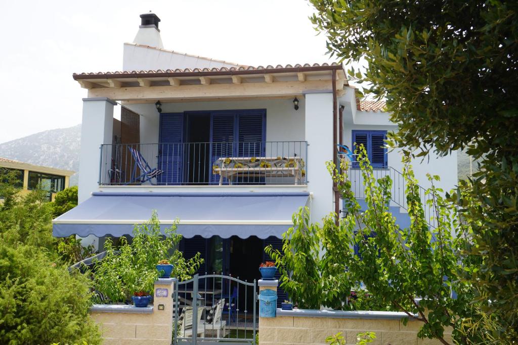 une maison blanche avec un balcon et des arbres dans l'établissement Casa Azzurra, à Cala Gonone