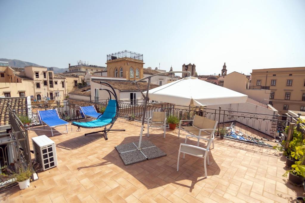a patio with chairs and an umbrella on a roof at Sunny loft with terrace and Jacuzzi in the city centre in Palermo