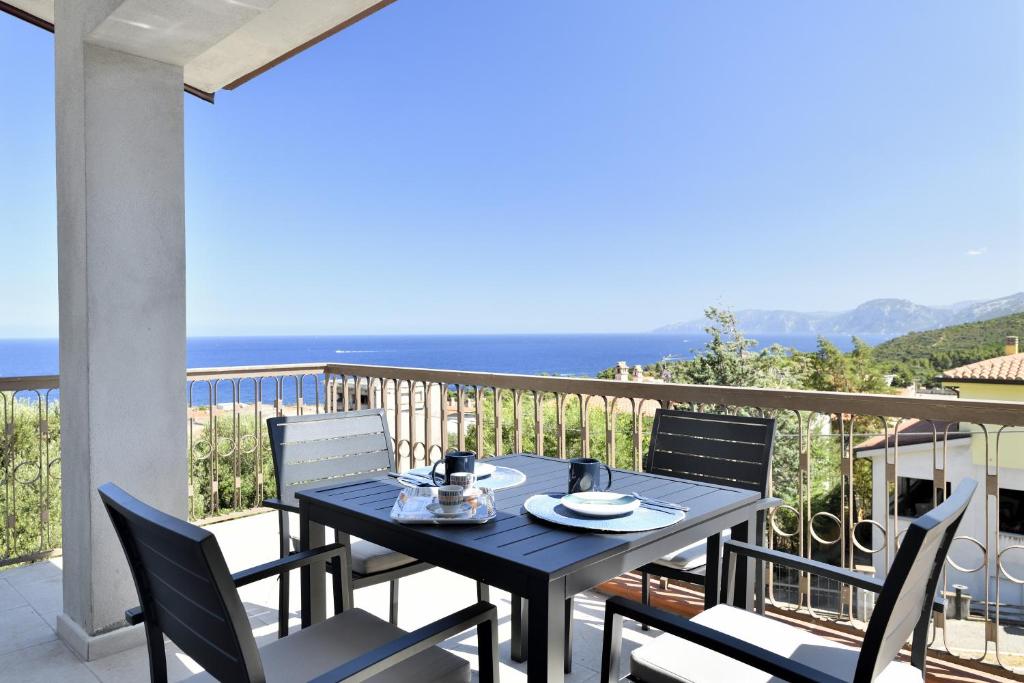 un tavolo e sedie su un balcone con vista sull'oceano di Appartamento vista Golfo a Cala Gonone