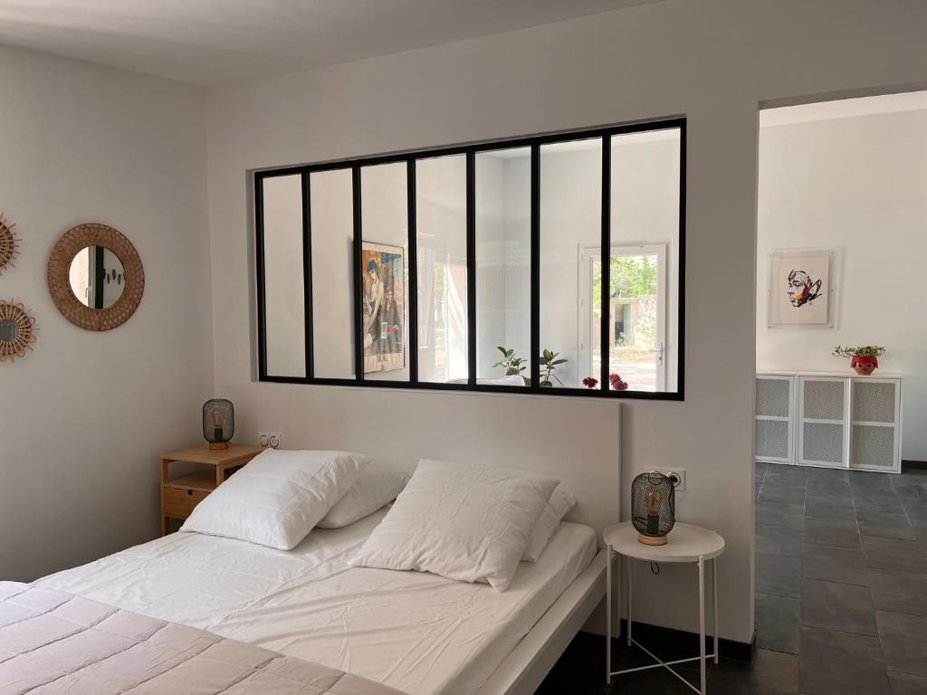 sypialnia z dużym białym łóżkiem i oknem w obiekcie Maisonnette indépendante avec jardin/patio w mieście Nîmes