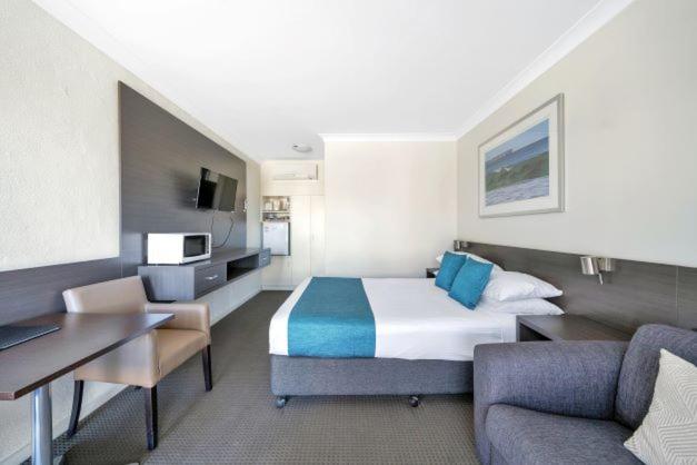 um quarto de hotel com uma cama king-size e uma secretária em Jervis Bay Motel em Huskisson