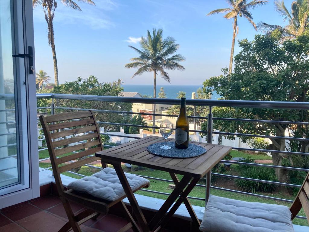 a table with a bottle of wine on a balcony at Cozy, 2 bedroom beachfront apartment in Ballito