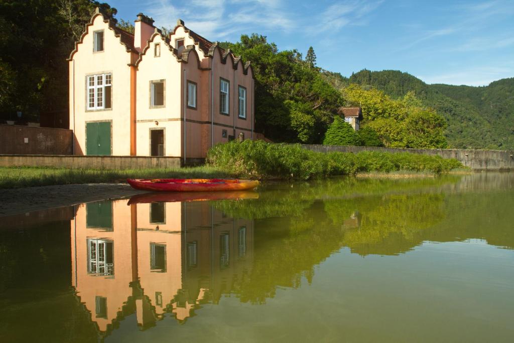 a house on the side of a river with a boat at Casa Dos Barcos Furnas in Furnas
