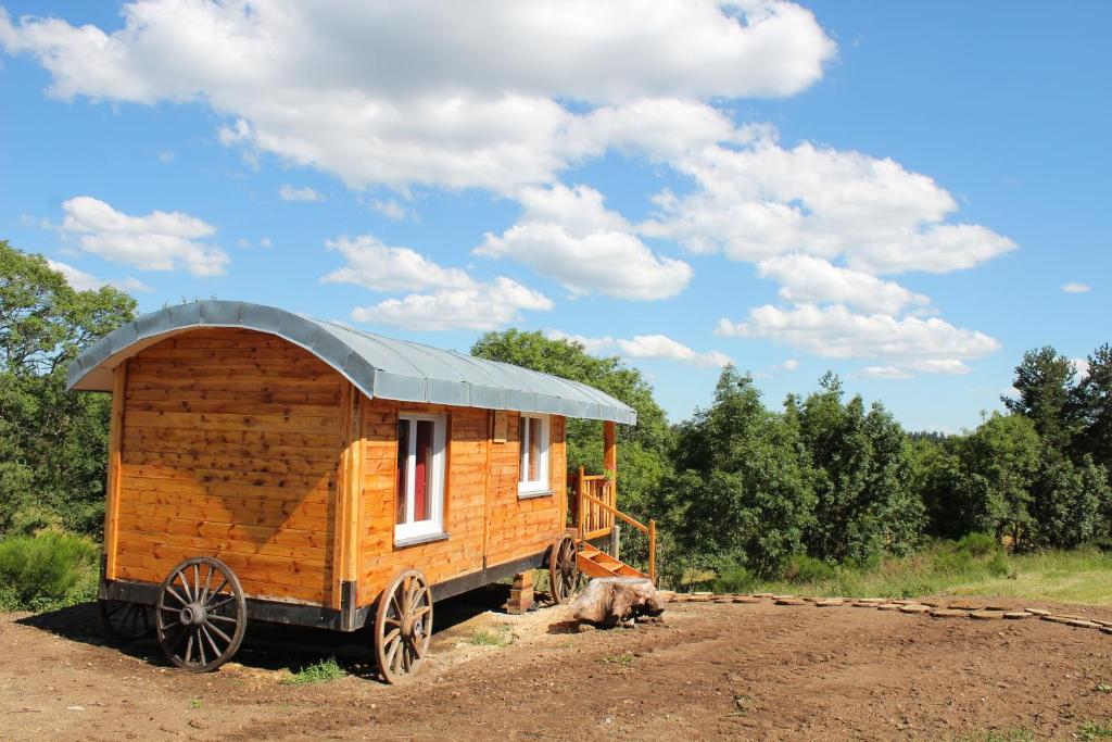 a wooden tiny house sitting on top of a field at roulotte impériale perchée- in Sembadel
