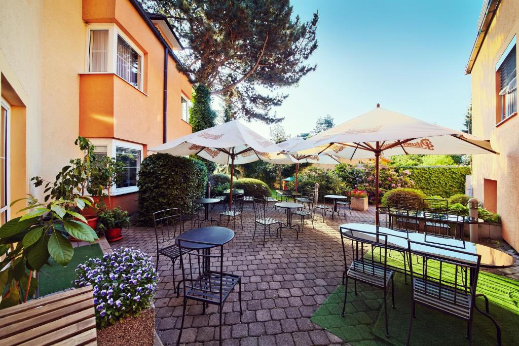 un patio con tavoli, sedie e ombrelloni di Hotel Tulipan Pruhonice a Pruhonice