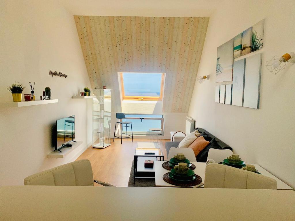 ein Wohnzimmer mit einem Sofa und einem Tisch in der Unterkunft Ático La Marosa -Vistas al Mar Cantabrico in Burela