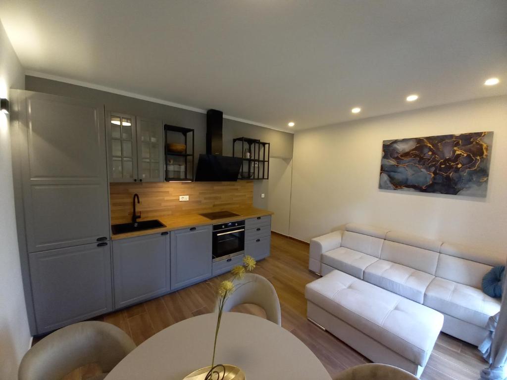 a living room with a white couch and a kitchen at Ferma in Makarska