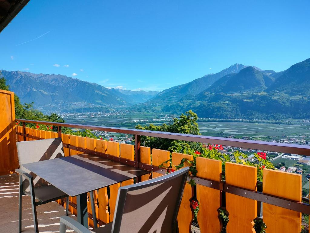 a table and chairs on a balcony with mountains at Georgenhöhe in Lana