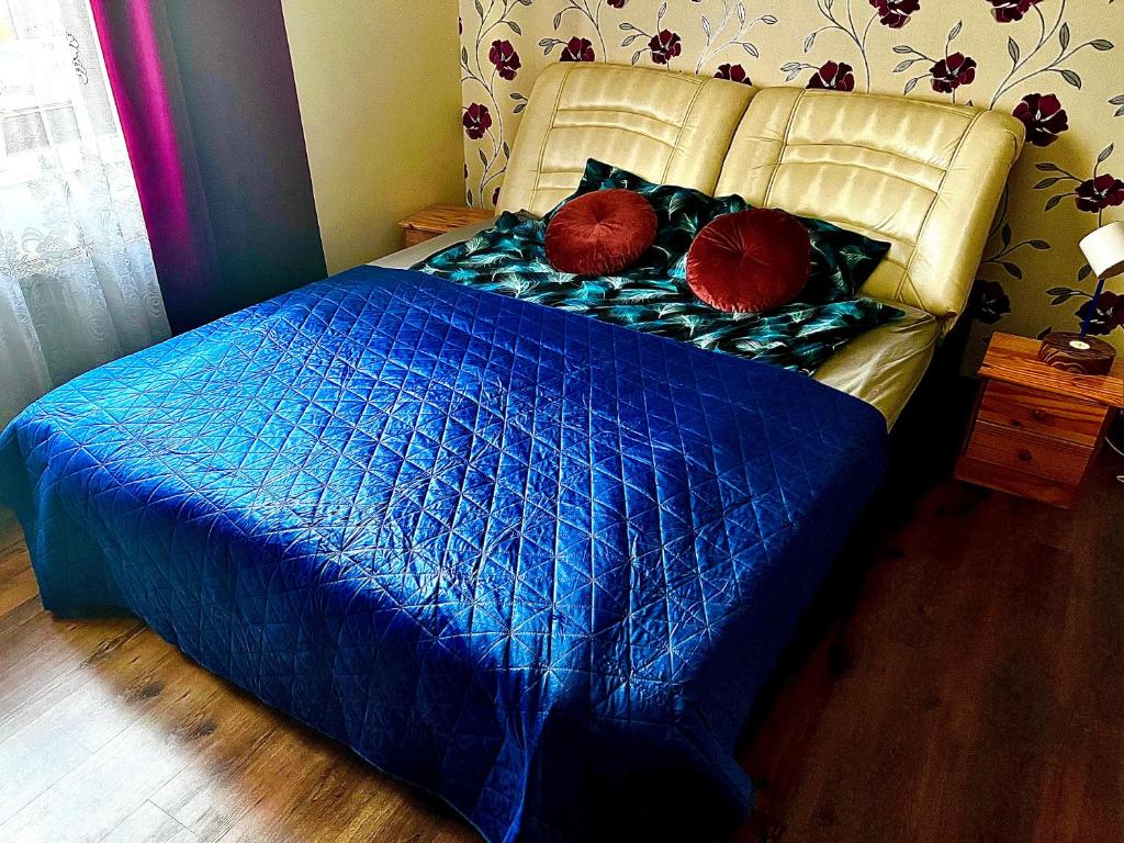 a blue bed with two red pillows on it at Villa Lake&Forest Trójmiasto in Dobrzewino