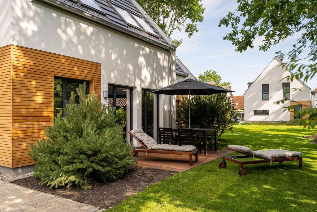 een patio met een tafel en stoelen en een parasol bij Hagebutte- Domizil am Ostseewald in Zingst