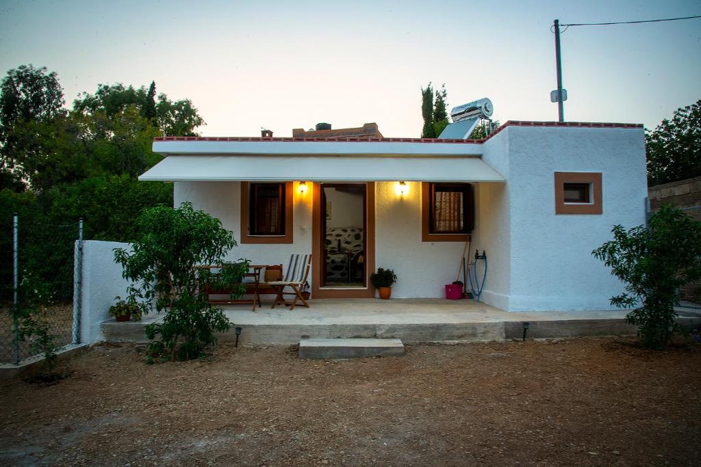 una pequeña casa blanca con un patio enfrente en Anemolia Tiny Stone House, en Palaikastro