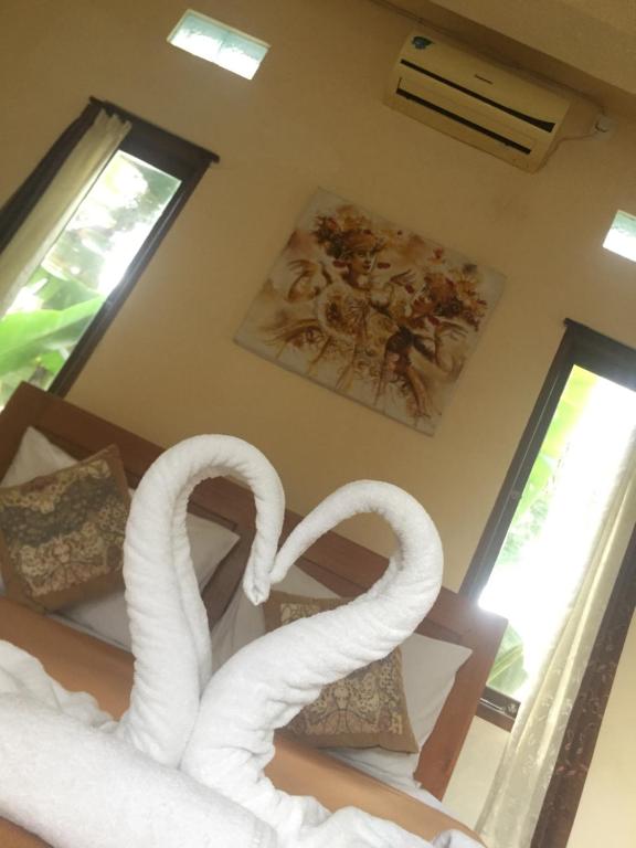 a couple of white swans in a bedroom at Kenari House in Ubud