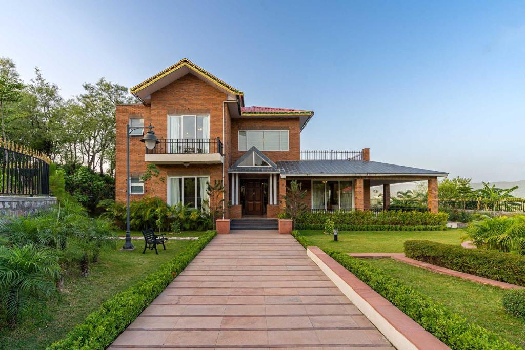 a brick house with a walkway in front of it at StayVista at Dhauladhar House - Aesthetic 4 BHK Villa in Kangra in Dharamshala