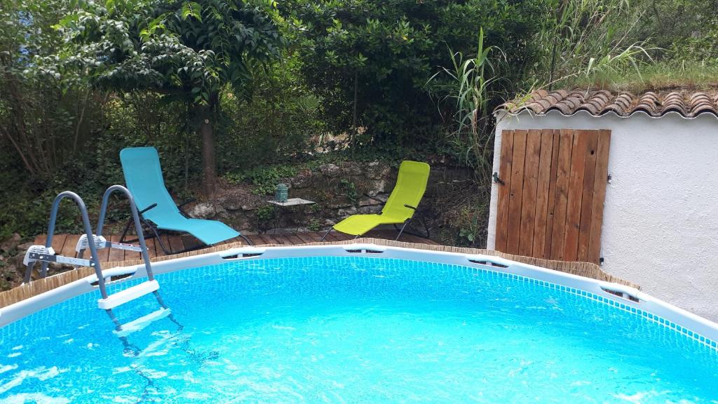 - une piscine avec 2 chaises et une table dans l'établissement Cocon en pleine nature avec piscine privative, à Junas