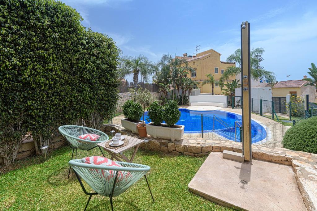 einen Garten mit zwei Stühlen und einem Pool in der Unterkunft WintowinRentals Adosado Premium en la Costa del Sol in Torre de Benagalbón