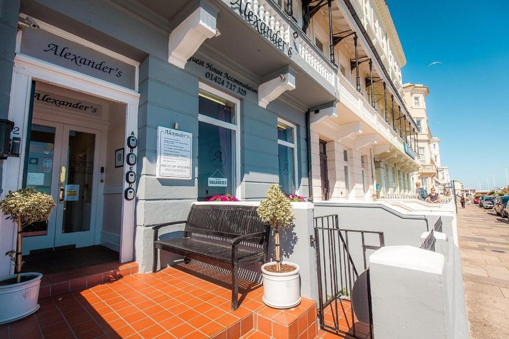 eine Bank, die vor einem Gebäude auf einem Bürgersteig sitzt in der Unterkunft Alexanders in Hastings