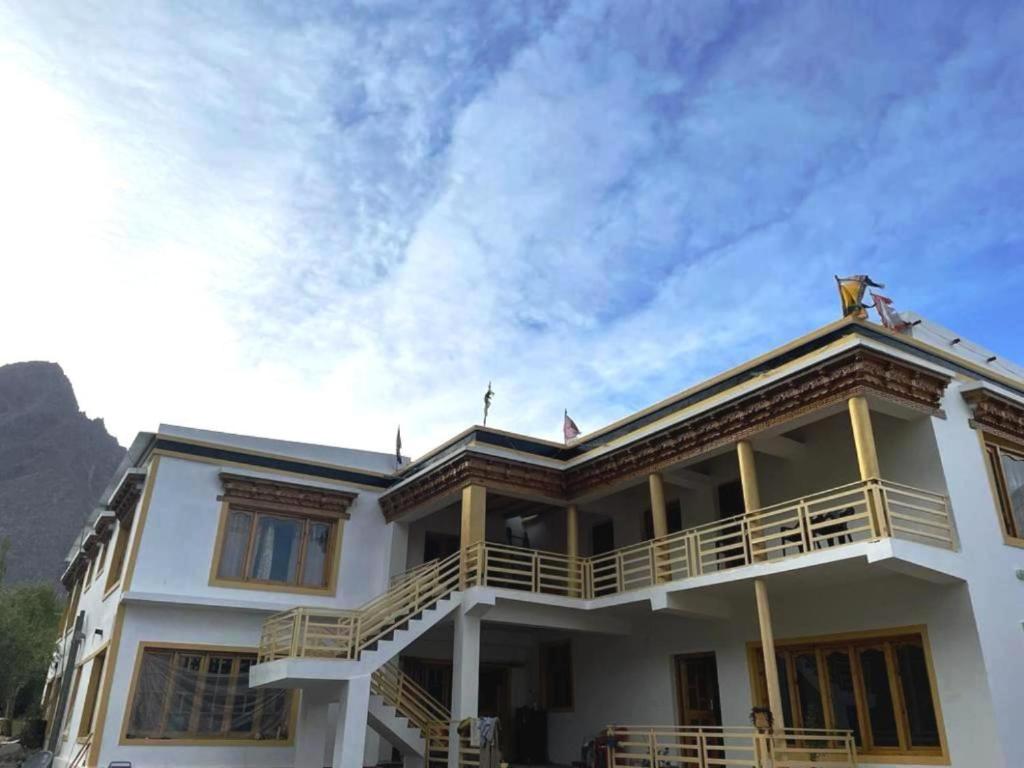 a white house with a balcony and a cloudy sky at Hotel Nubra Delight and Camps in Hundar