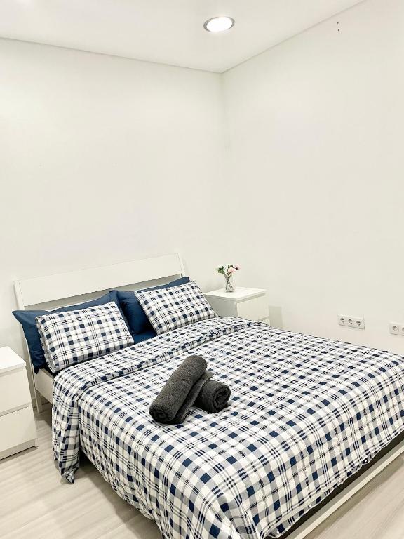 ein weißes Schlafzimmer mit einem Bett mit einer schwarz-weißen karierten Decke in der Unterkunft Lisboa New in Bobadela