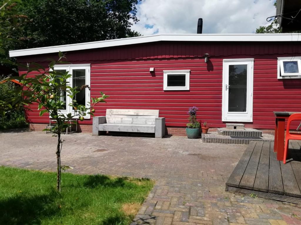 a red building with a bench in front of it at Huisje VOS in Schoonloo