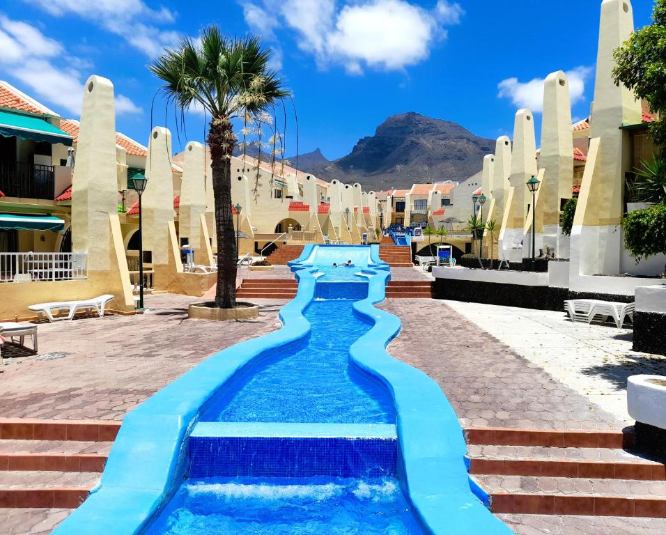een zwembad in een resort met een palmboom en gebouwen bij Fantastic 3 Bedrooms MAREVERDE, WIFI free in Adeje