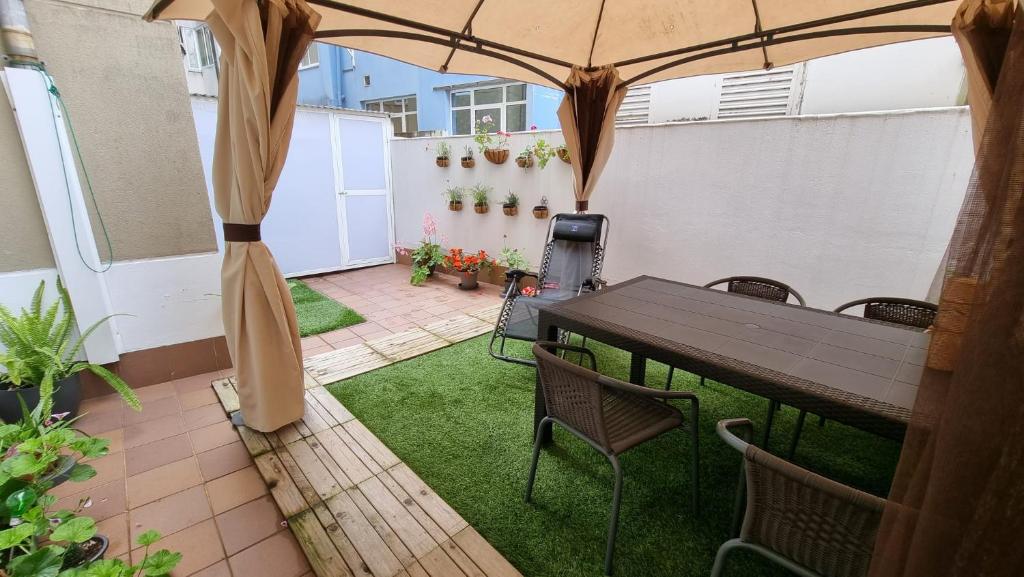 une terrasse avec une table et des chaises sous un parasol dans l'établissement Piso con terraza en Villagarcia de Arosa, à Vilagarcía de Arousa