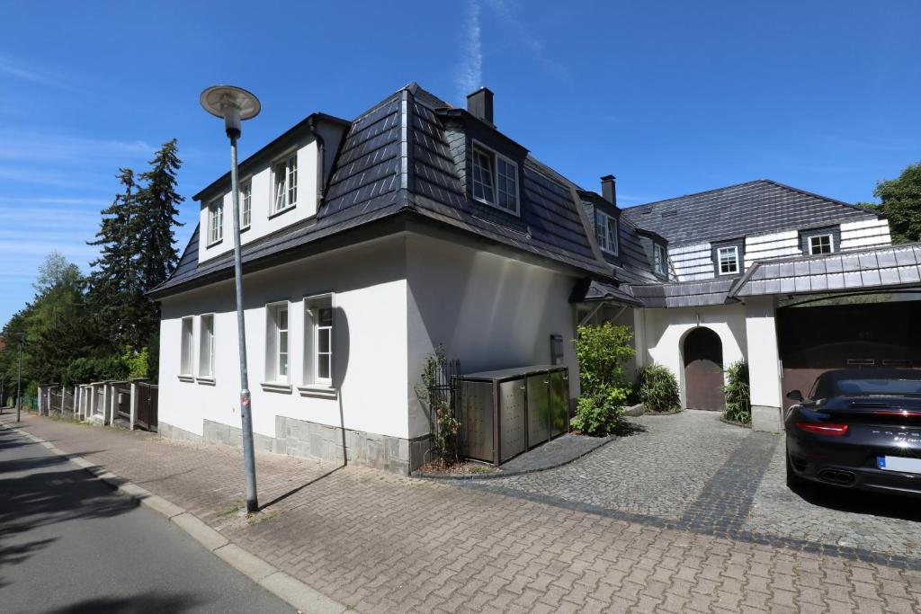 a white house with a black roof on a street at BohnApartments Steigerwald - Natur in der Stadt - Vollausstattung - WLAN - gratis Parkplätze in Erfurt