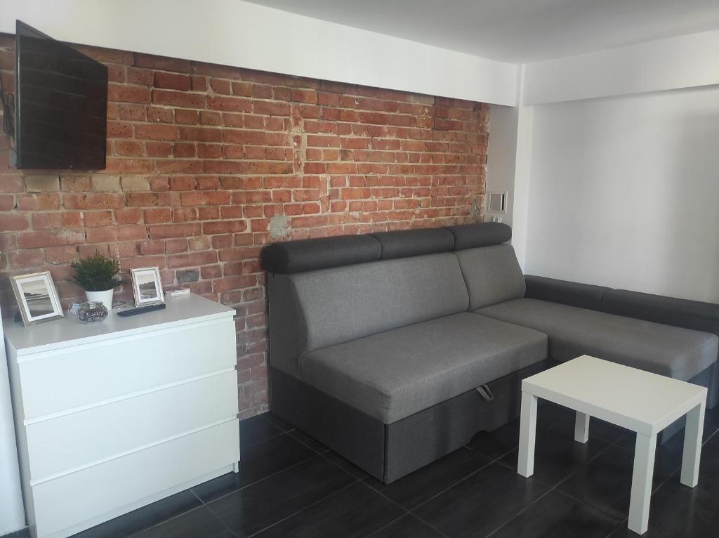 ein Wohnzimmer mit einer Couch und einer Ziegelwand in der Unterkunft Apartament przy plaży in Danzig