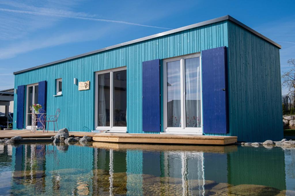 a blue building sitting on top of a body of water at Tiny-House mit großer Terrasse zum Genießen! 