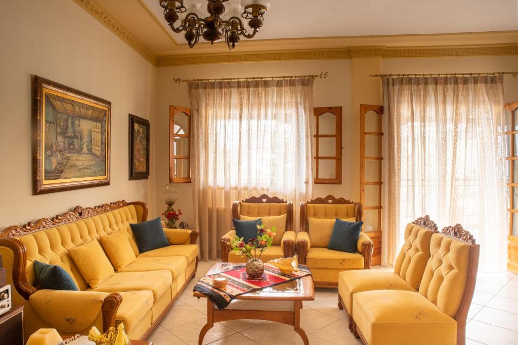 a living room with yellow couches and a table at Violetta's House Παραδοσιακή Βίλα στην Πορταριά in Portaria