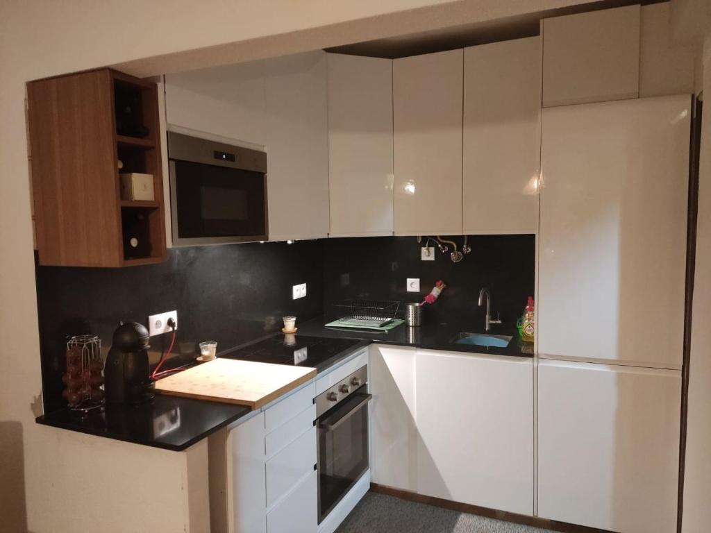 a kitchen with white cabinets and a black counter top at Caparica Apartment near beach in Costa da Caparica
