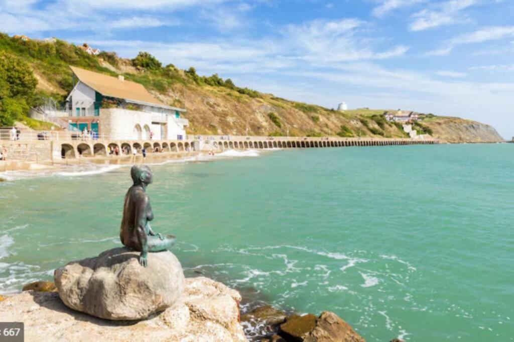 a statue of a mermaid sitting on a rock near the water at Beautifully appointed, period seaside apartment in Folkestone