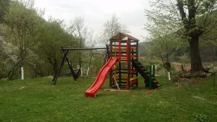 a playground with a red slide in a field at Pensiune Piatra Mare in Nehoiu