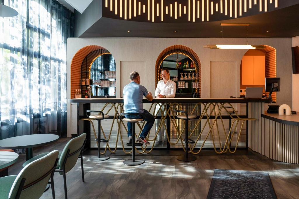 Dois homens sentados num bar num restaurante. em ibis Styles Paris Porte de Versailles - Mairie d'Issy em Issy-les-Moulineaux