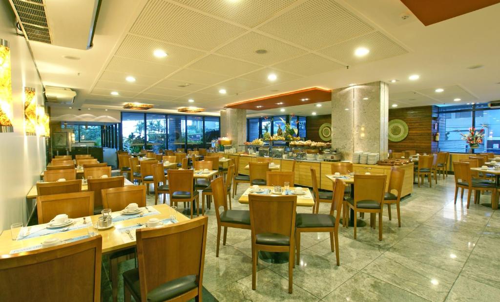 um restaurante com mesas e cadeiras de madeira e um bar em Hotel Diogo em Fortaleza