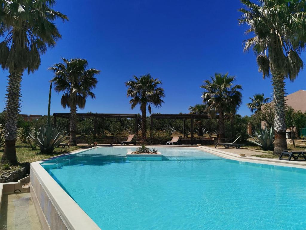 una piscina con palmeras en el fondo en La Masseria - Rainbow Hotel LGBT - Adults Only en Campofelice di Roccella