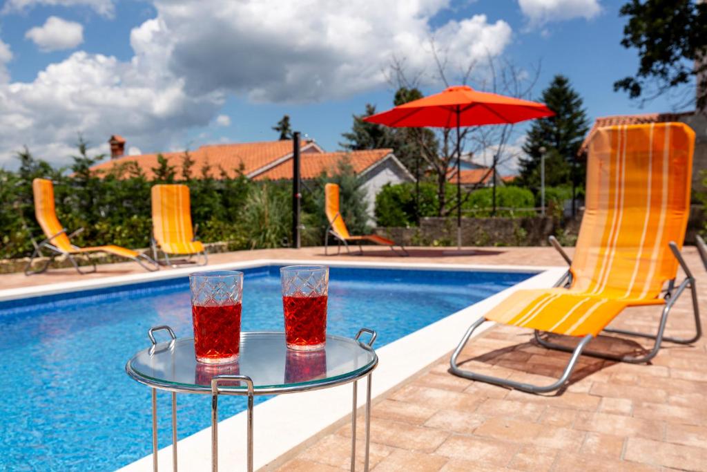 a table with two glasses on it next to a pool at Casa Lilly in Labin
