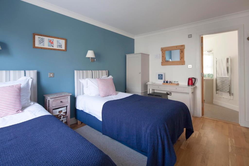 a bedroom with two beds with blue walls at The Artist Loft, Ensuite Guest Rooms, Porthleven in Porthleven