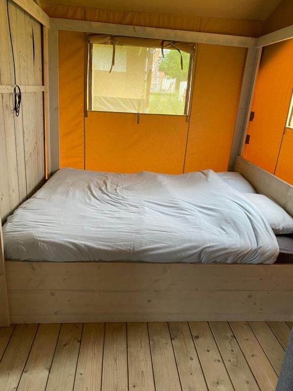 Bett in einem kleinen Zimmer mit Fenster in der Unterkunft BG Apartments Safaritent in Somogyhatvan
