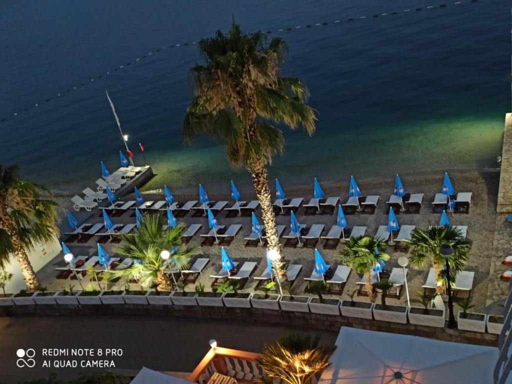 un hotel con sillas azules y un barco en el agua en Hotel Azzurro, en Herceg-Novi