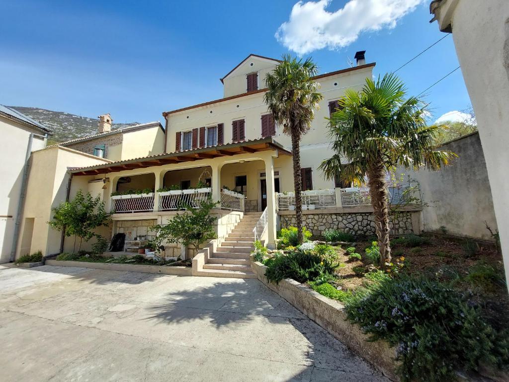 a large house with palm trees in front of it at Rooms Nada in Tribalj