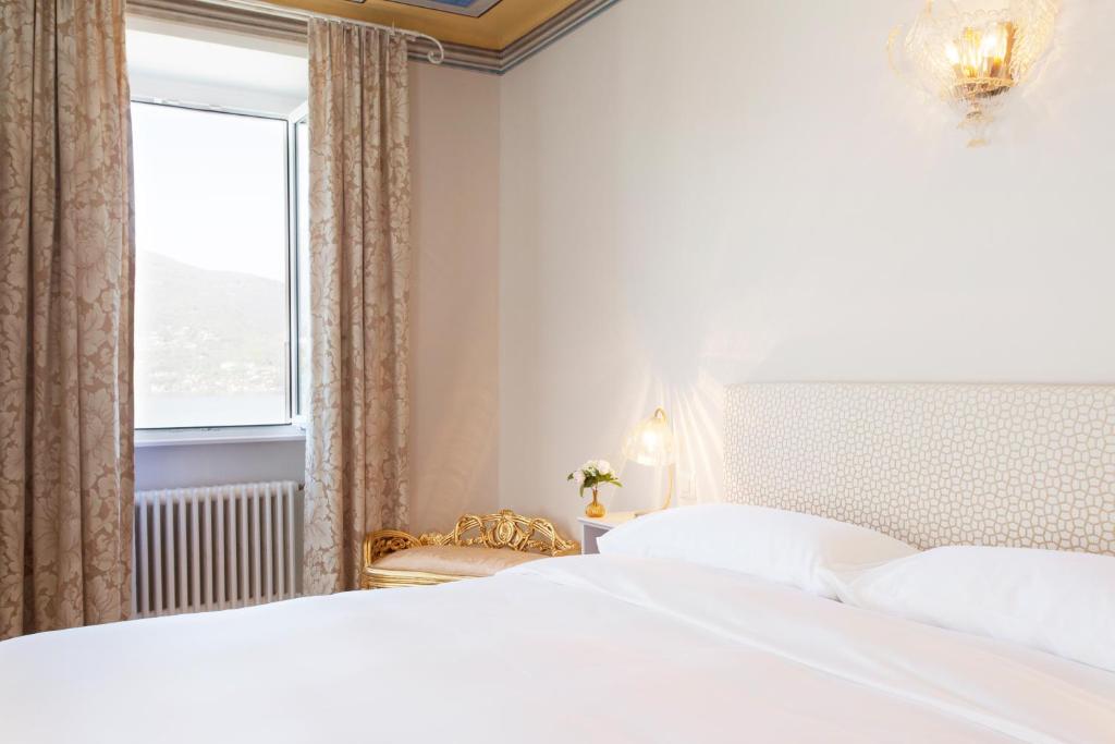 a bedroom with two white beds and a window at Boutique Hotel Villa Sarnia in San Nazzaro