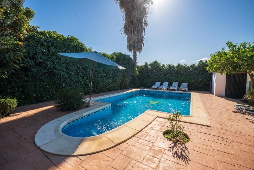 a swimming pool with an umbrella and two chairs and an umbrella at Cortijo Vélez in Trapiche