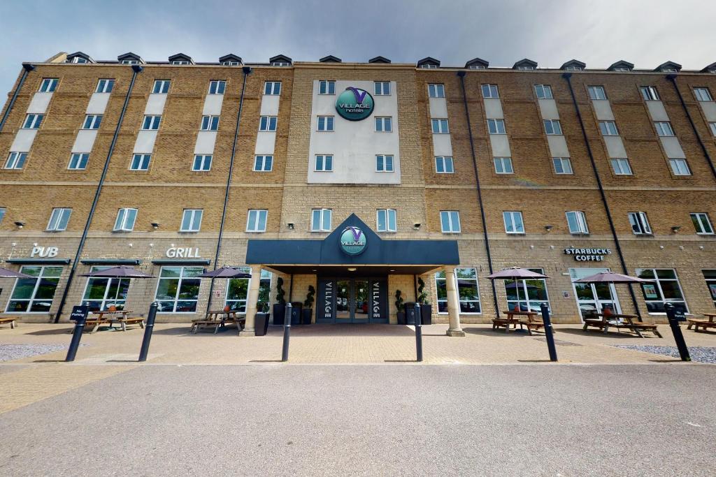 a hotel front of a building with tables and chairs at Village Hotel Bournemouth in Bournemouth