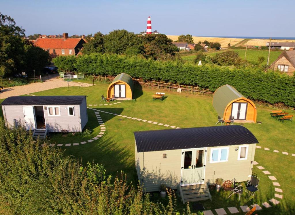 a group of tiny homes in a field at Lanterns Shepherds Huts & Glamping in Happisburgh