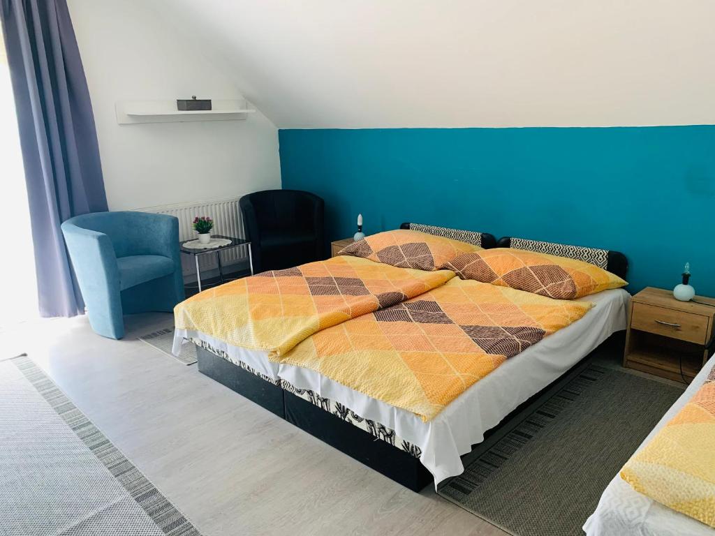 ein Schlafzimmer mit einem Bett und einer blauen Wand in der Unterkunft Gulyás Vendégház in Bük